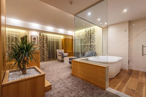 a bathroom with a large tub and a large mirror at Hotel Bellevue in Trebinje