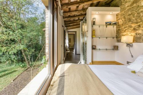 a bedroom with a bed and a large window at La Pallissa - Can Bonet in Sant Martí Vell