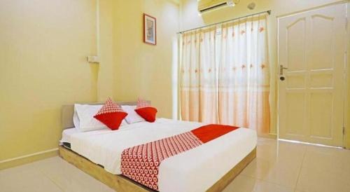 a bedroom with a bed with red pillows and a window at Hotel O Wisma Pinggir in Tanjung Pinang 