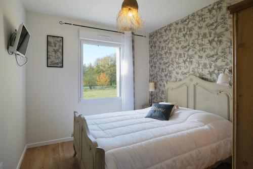 ein Schlafzimmer mit einem großen weißen Bett mit einem Fenster in der Unterkunft La petite maison dans la prairie in Néant-sur-Yvel