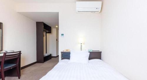 a bedroom with a white bed with a desk and a chair at Tabist Hotel New Osamura Sabae in Sabae