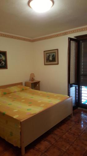 een slaapkamer met een groot bed met een geel dekbed bij Casa Bandinu in Budoni