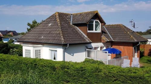 a white house with a brown roof on a hill at Herich in Nieblum