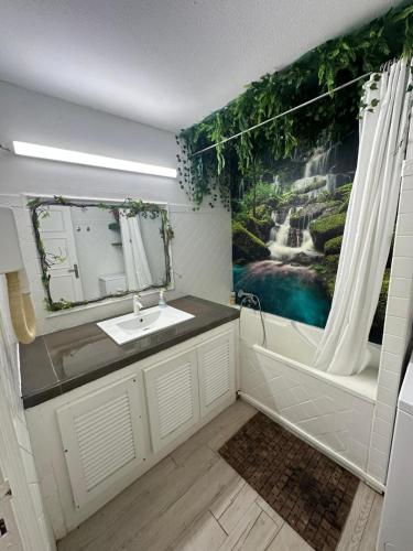 a bathroom with a sink and a waterfall painting on the wall at Studio avec jardin et piscine in Saint-François