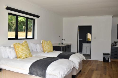 a bedroom with two white beds with yellow and black pillows at Mable's BnB in Retreat