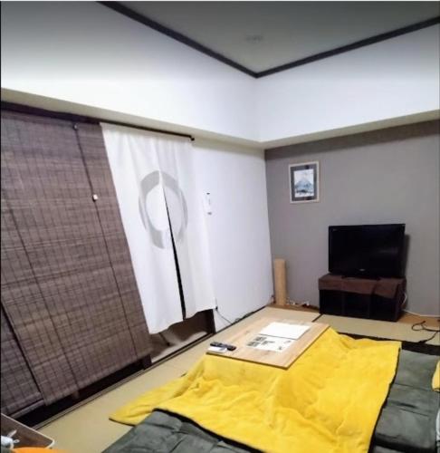 a bedroom with a yellow bed and a television at 板橋 RCアネックス Rc305Rc306Rc307 in Tokyo