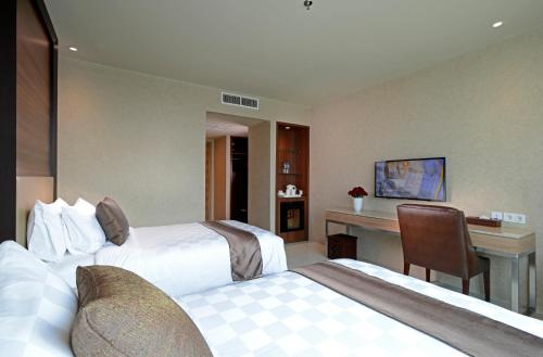 a hotel room with two beds and a desk at Aria Centra Surabaya in Surabaya