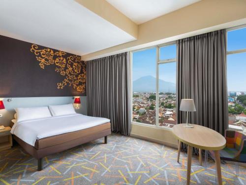 a hotel room with a bed and a large window at Ibis Styles Malang in Malang