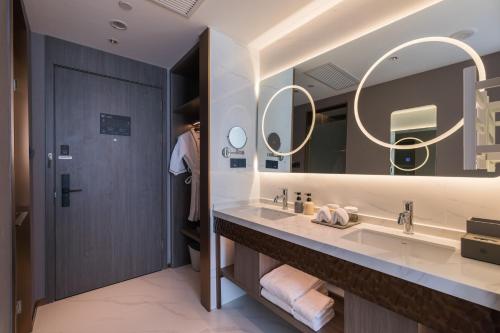 a bathroom with a large sink and two mirrors at Langliz Hotel Capital Airport New International Exhibition Center Branch in Beijing