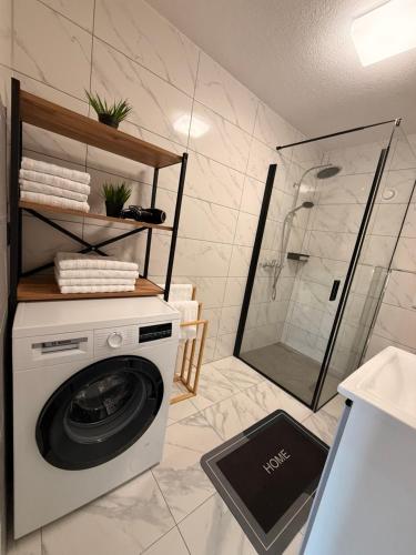 uma máquina de lavar roupa na casa de banho com um chuveiro em Apart Alpenglow Imst em Imst