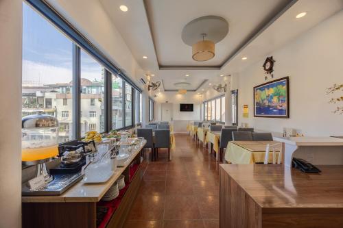 a dining room with tables and chairs and windows at A25 Hotel - 35 Mạc Thị Bưởi in Ho Chi Minh City