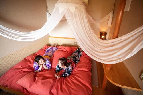 two children are laying on a bed at Rurika in Izu
