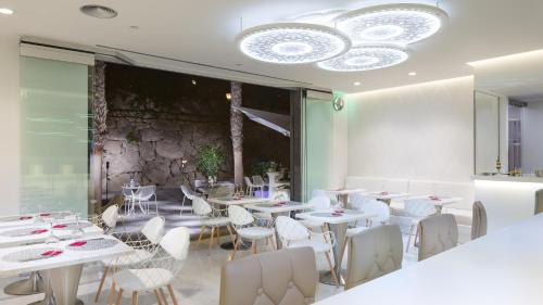 a restaurant with white tables and chairs and a chandelier at Gran Tacande Wellness & Relax Costa Adeje in Adeje