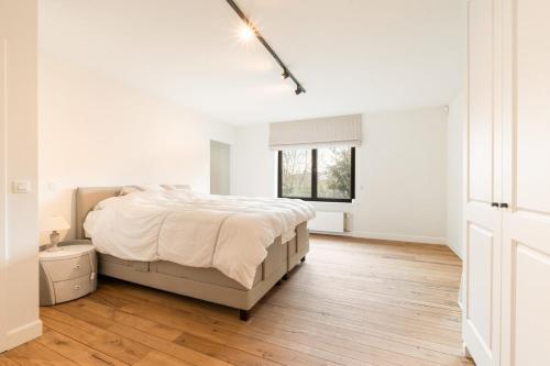 a white bedroom with a bed and a wooden floor at exceptional luxury villa near Knokke Golf in Knokke-Heist