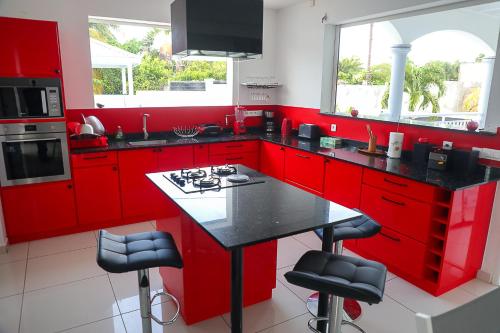 een keuken met rode kasten en een zwart aanrechtblad bij NAHEFLEURS in Sainte-Anne