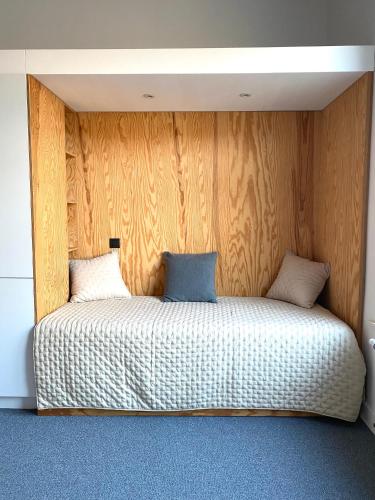łóżko w pokoju z drewnianą ścianą w obiekcie Canopée guesthouse w Brukseli