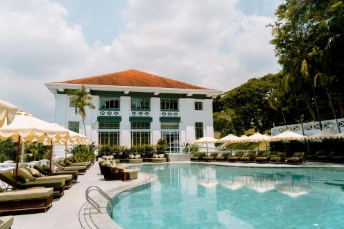 a pool with chairs and umbrellas in front of a building at METT Singapore in Singapore