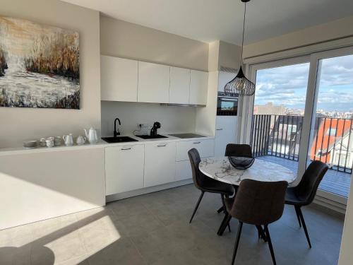 a kitchen with white cabinets and a table with chairs at Zeebries Penthouse in Koksijde