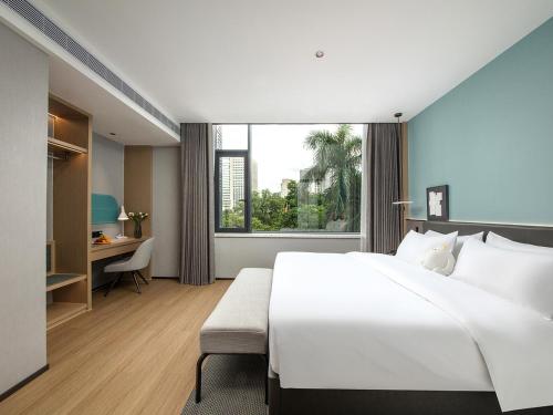 a large white bedroom with a large bed and a desk at The Liyi Hotel Guangzhou Taikoo Hui Huashi Metro Station Branch in Guangzhou