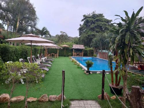 un complejo con piscina, sillas y sombrilla en Siam Flora Resort Koh Lanta, en Ko Lanta