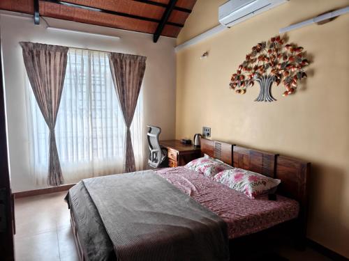 Un dormitorio con una cama y un árbol en la pared. en Suseelagam, en Sīrkāzhi