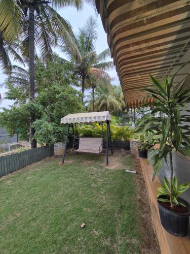a bench under awning in a yard with palm trees at Charu's Villa By Elite Stays in Jāmb
