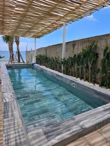a large swimming pool with a wooden roof at Warm Way Beach Villas in Bình Sum