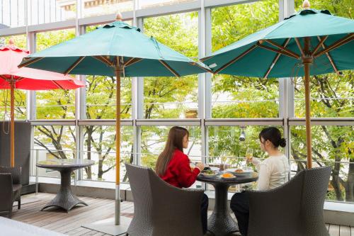 two women sitting at a table under umbrellas at KOKO HOTEL Kobe Sannomiya in Kobe