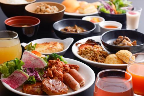 a table with plates of food and glasses of juice at KOKO HOTEL Kobe Sannomiya in Kobe