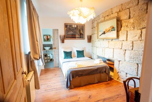 a bedroom with a bed and a brick wall at Domaine de Venoise, Château 31 personnes in Noyers-sur-Serein