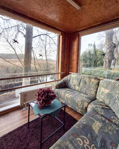 a living room with a couch and a large window at Sodyba prie Mūšos in Pamūšis