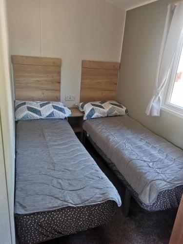 two beds in a small room with a window at Thornesbay holiday park in Isle of Wight