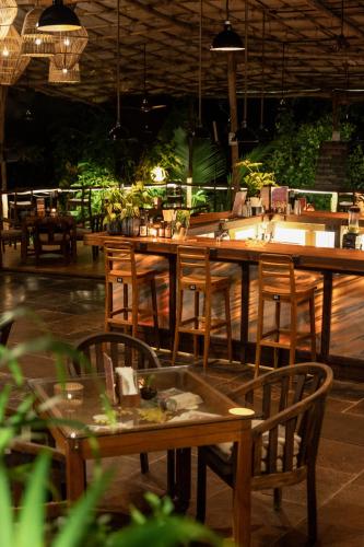 a restaurant with wooden tables and chairs and lights at Mojigao - Eco Resort in Assagao