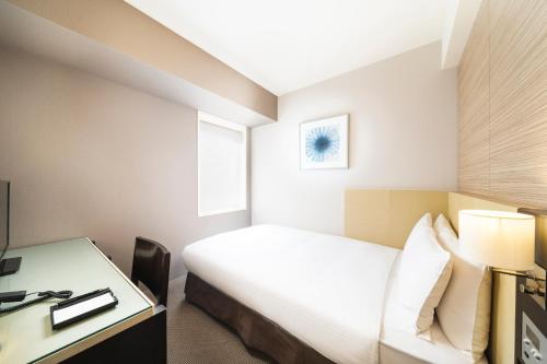 a hotel room with a bed and a desk at KOKO HOTEL Kobe Sannomiya in Kobe