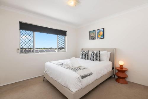 a white bedroom with a large bed and a window at Pine Street Apartments Bulimba in Brisbane