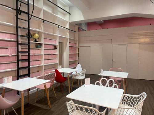 大阪Cafe&Hostel Kimi to Ichigo的一个房间里有白色的桌椅和粉色的椅子