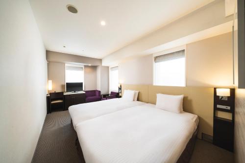 a hotel room with a bed and a desk at KOKO HOTEL Kobe Sannomiya in Kobe