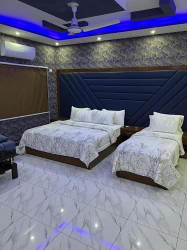 two beds in a room with blue lights at Defence Orchard DHA in Dargai