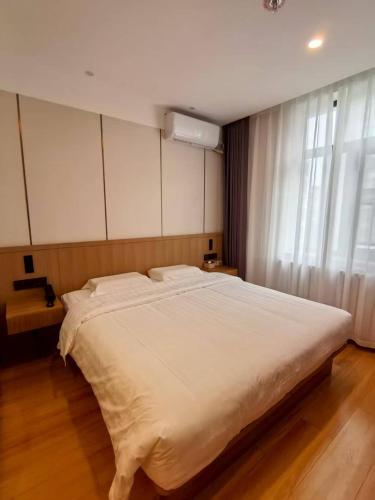 un grand lit blanc dans une chambre avec une fenêtre dans l'établissement Beijing Northern Langyue Hotel Financial Street Branch, à Pékin