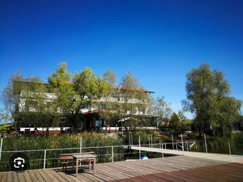 ein Gebäude mit einem Tisch und einer Bank auf einem Holzsteg in der Unterkunft Pensiunea Lac Calinesti 