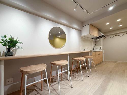 a kitchen with stools and a counter with a mirror at Clio Matoba by b hotel - Fully Equipped Urban Studio Peaceful Stay in Ōsukachō