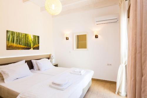 a bedroom with a white bed with towels on it at Kampos Villa 1 in Achlades