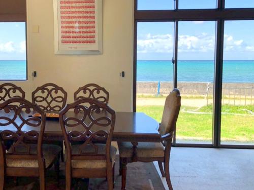a dining room with a table and chairs and the ocean at SEA BASE Onna in Onna