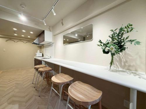 a bar with stools and a vase of flowers at Clio Matoba by b hotel - Fully Equipped Studio 10min to Hiroshima Station in Ōsukachō
