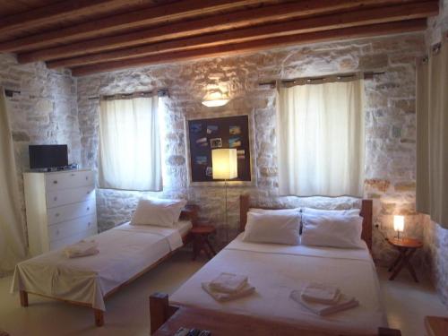 a bedroom with two beds and a stone wall at Naousa in Naousa