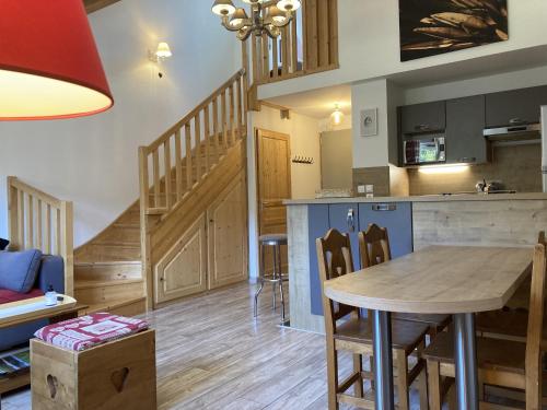a kitchen and living room with a table and a staircase at T2 avec vue sur les montagnes et wifi in Le Lioran