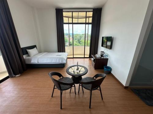 una habitación con una cama, una mesa y sillas en Glistar Hotel, en Tampin