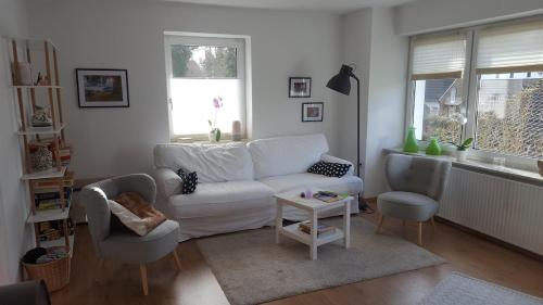 a living room with a white couch and two chairs at FerienwohnungHunteblick in Wildeshausen