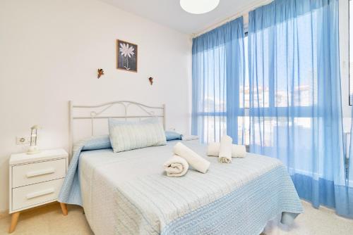 Schlafzimmer mit einem Bett mit blauen Vorhängen in der Unterkunft Apartamento Con Parking Y Piscina in Castillo Bajo