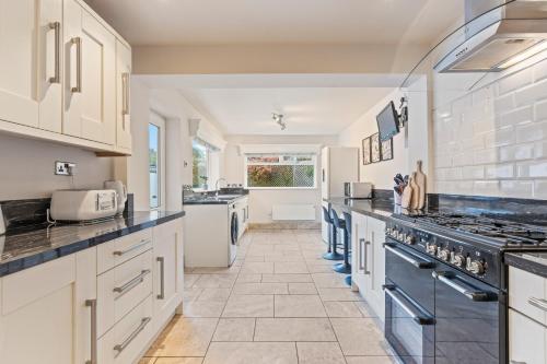 a large kitchen with white cabinets and black appliances at Luxury Escape Sleeps 7 in Albrighton- 4 Beds 3 Double beds 1 single 2 Mins to M54 RAF Cosford Shifnal Telford Oxley Staffordshire -JLR Wolves Stafford I54 Business Park- 10 Mins to M6- 40 Mins to NEC Regular & Long Work Stays available - Samina- ARZ Stays in Albrighton